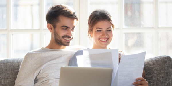 Happy young couple relax on sofa read paperwork