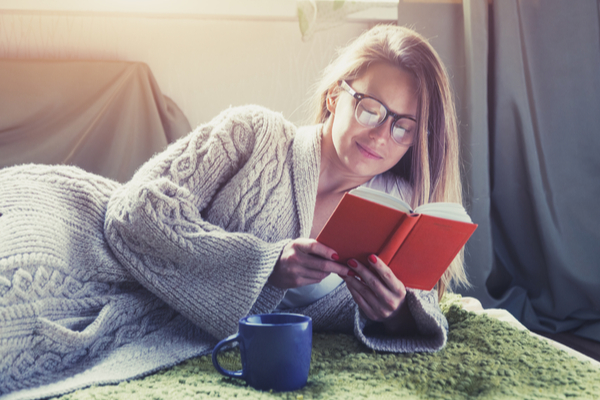 Woman relaxing on the bed and reading a book