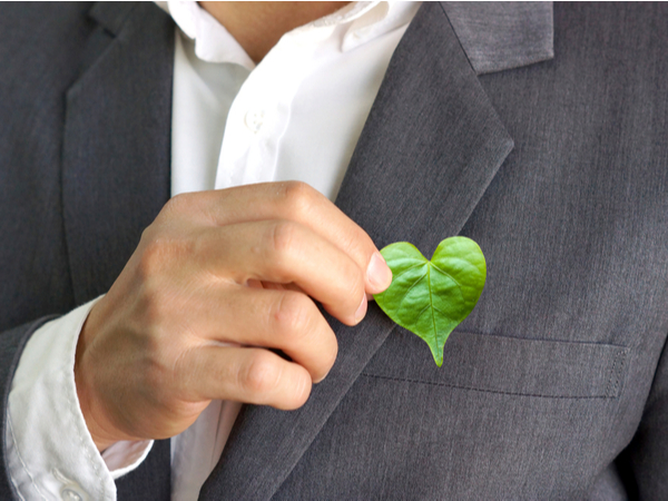 Man wearing a coat holding a heart-shaped leaf