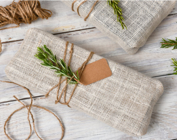StepUp - What should you buy for Christmas Fabric wrapped Christmas presents placed on a rustic wood table.