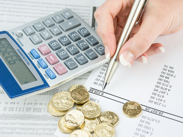 Woman computing her funds with coins and calculator on top of the paper