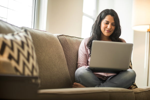 Woman sitting at the couch using her laptop