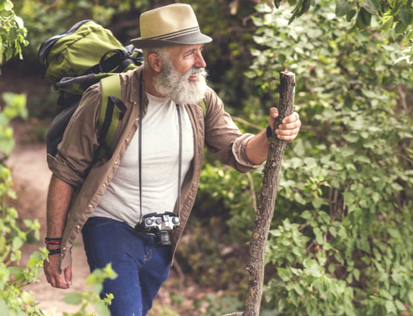 Step Up - Active years Senior male hiker walking with backpack in the wood