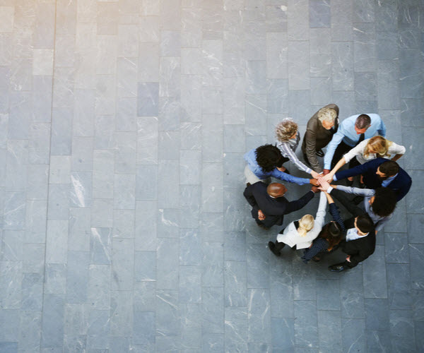 Step Up - Growing financial team a team of united businesspeople standing with their hands together in a building