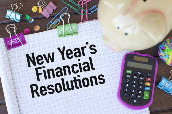 New Year's Financial Resolutions written on a pad with clips, calculator and piggy bank