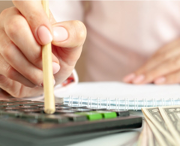Step Up - Make a budget Hand of a woman with calculator counting and taking notes to notebook