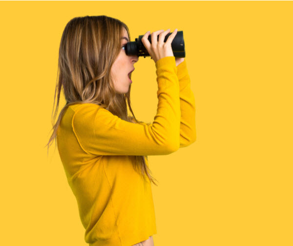 SU - Lost Super and Consolidate young girl with yellow sweater and looking in the distance with binoculars on isolated yellow background
