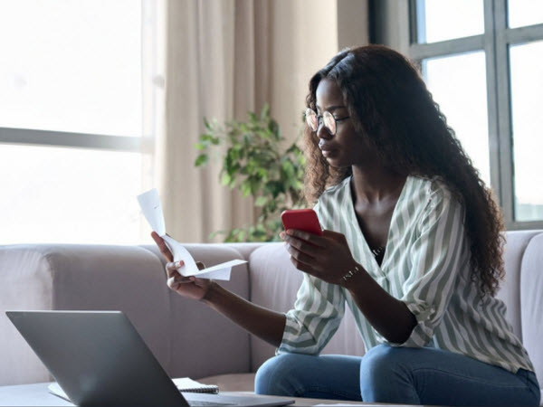 Serious young African woman holding paper document calculating rent or money savings