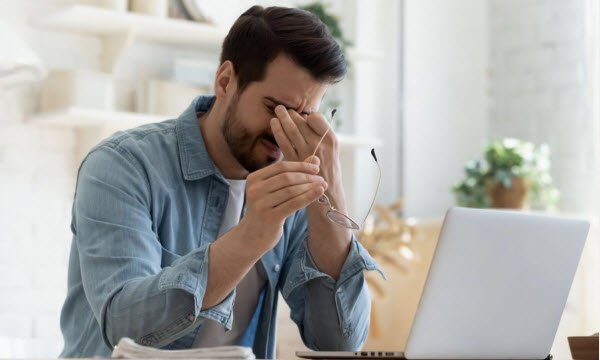 SU - Tips to cope with rising inflation Tired young man feel pain eyestrain holding glasses rubbing dry irritated eyes fatigued from computer work