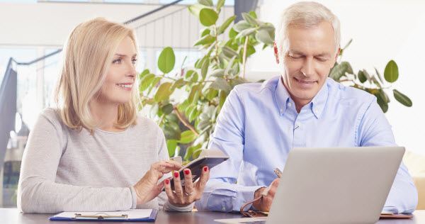 Couple sitting at home in front of laptop and manage their monthly budget