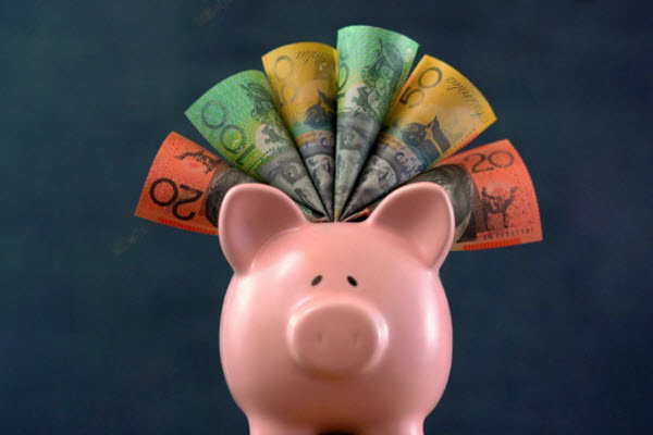 Pink Piggy bank money concept on dark blue background, stuffed with Australian cash