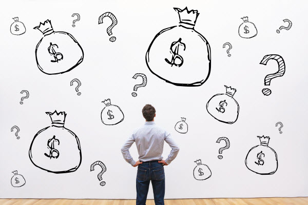 Businessman looking at the wall with question marks and dollar signs