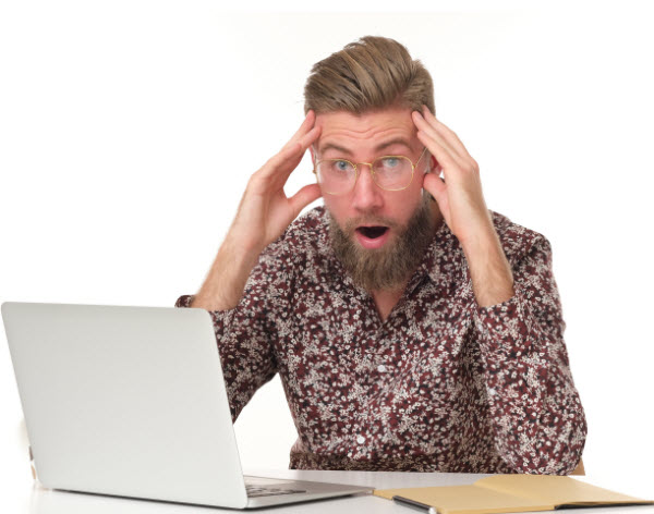 Shocked man with beard putting his two hand on his head while in front of the laptop