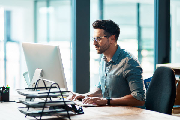 Step Up Group - Stay consistent with investments Focused young businessman using a computer at his desk