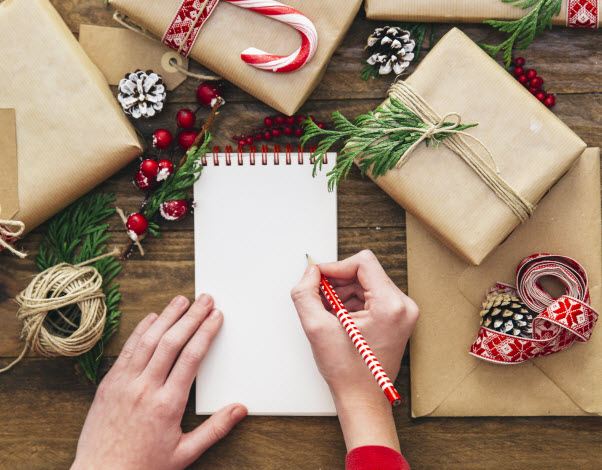 Step Up Group - Making a budget list Woman writing on a notepad with Christmas decorations on the table