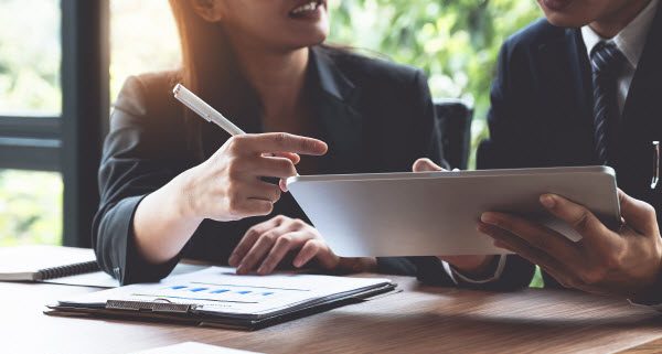 Step Up Group - Understanding high-yield investments Team of professionals discussing about stocks and financial graph using a tablet