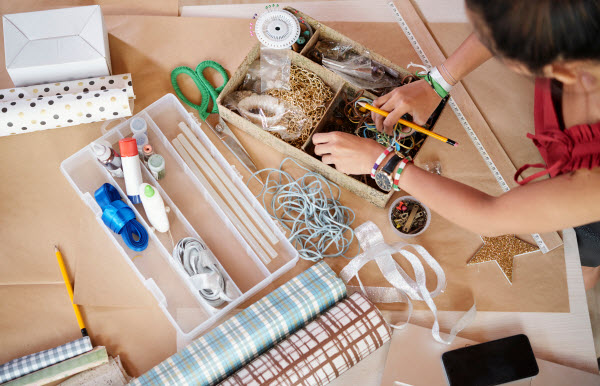 Step up Group - Get creative woman sitting at the table and making handmade present from different ribbons, beads and gift papers