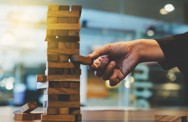 Step Up - Risks of ESG investing hand of businessman pulling out or placing wood block on the tower in modern office