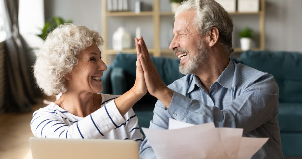 Happy couple giving high five to each other while holding documents