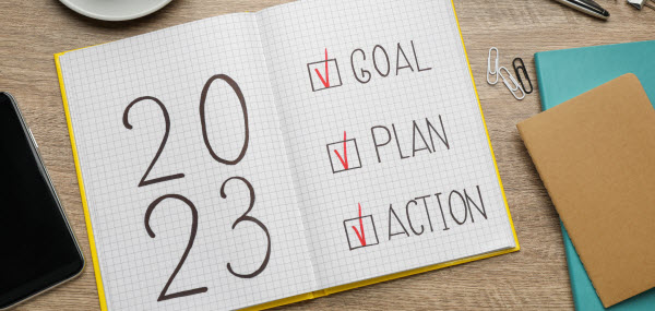 notebook with text 2023 Goal, Plan, Action on wooden table