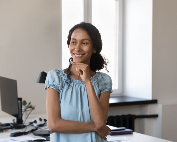 Smiling lady standing beside her office table
