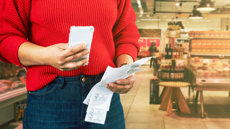 Step Up - Shop around woman checking grocery cost using calculator in smartphone compare prices with receipts from previous month in supermarket