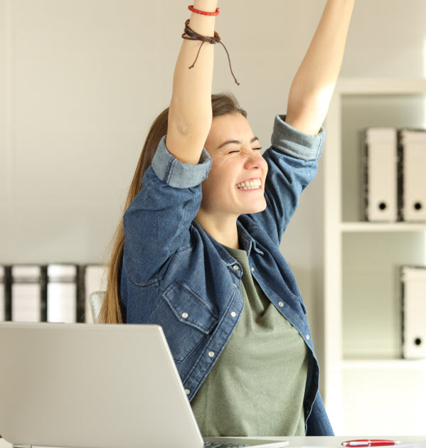young satisfied intern raising arms at office
