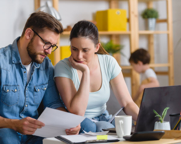 Married couple stressed with the bills while son is cleaning at the living room