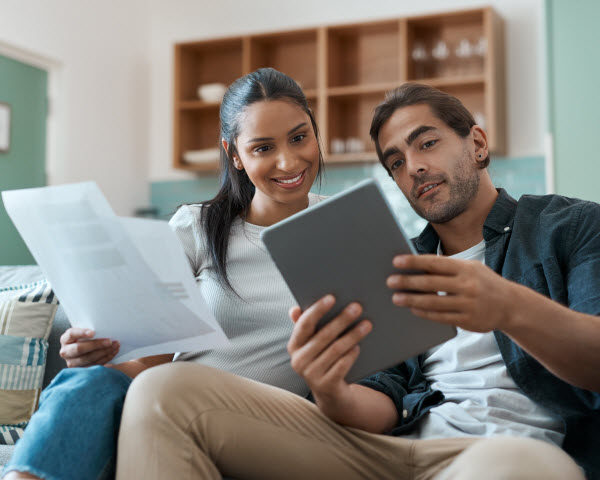 Step Up - Strategise property purchase couple doing paperwork while using a digital tablet at home