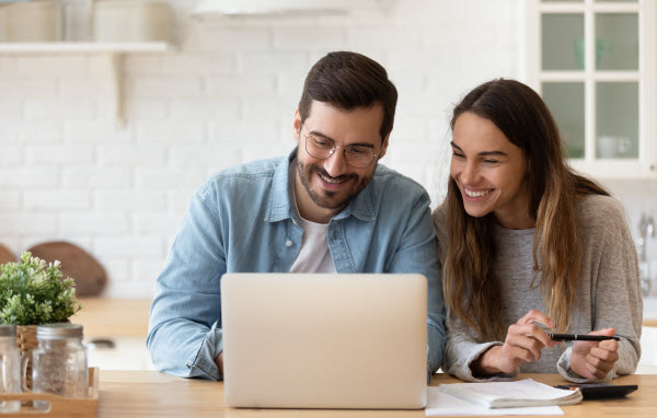 Step Up - Best investment option Happy young couple planning budget using laptop while in the kitchen