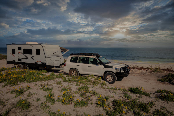 4WD modern caravan camping alongside a sunny beach
