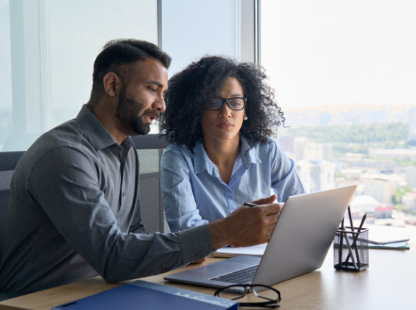 Step Up - Choose right investment options Man teaching his colleague, discussing using laptop