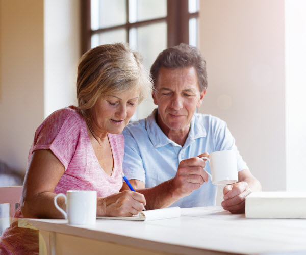 Happy senior couple sitting at the table making plans and drinking coffee