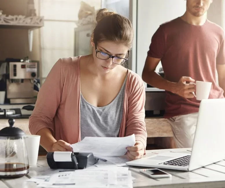 Young woman doing accounts together with her husband at home