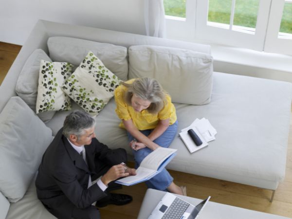 mature woman sitting on sofa with financial advisor