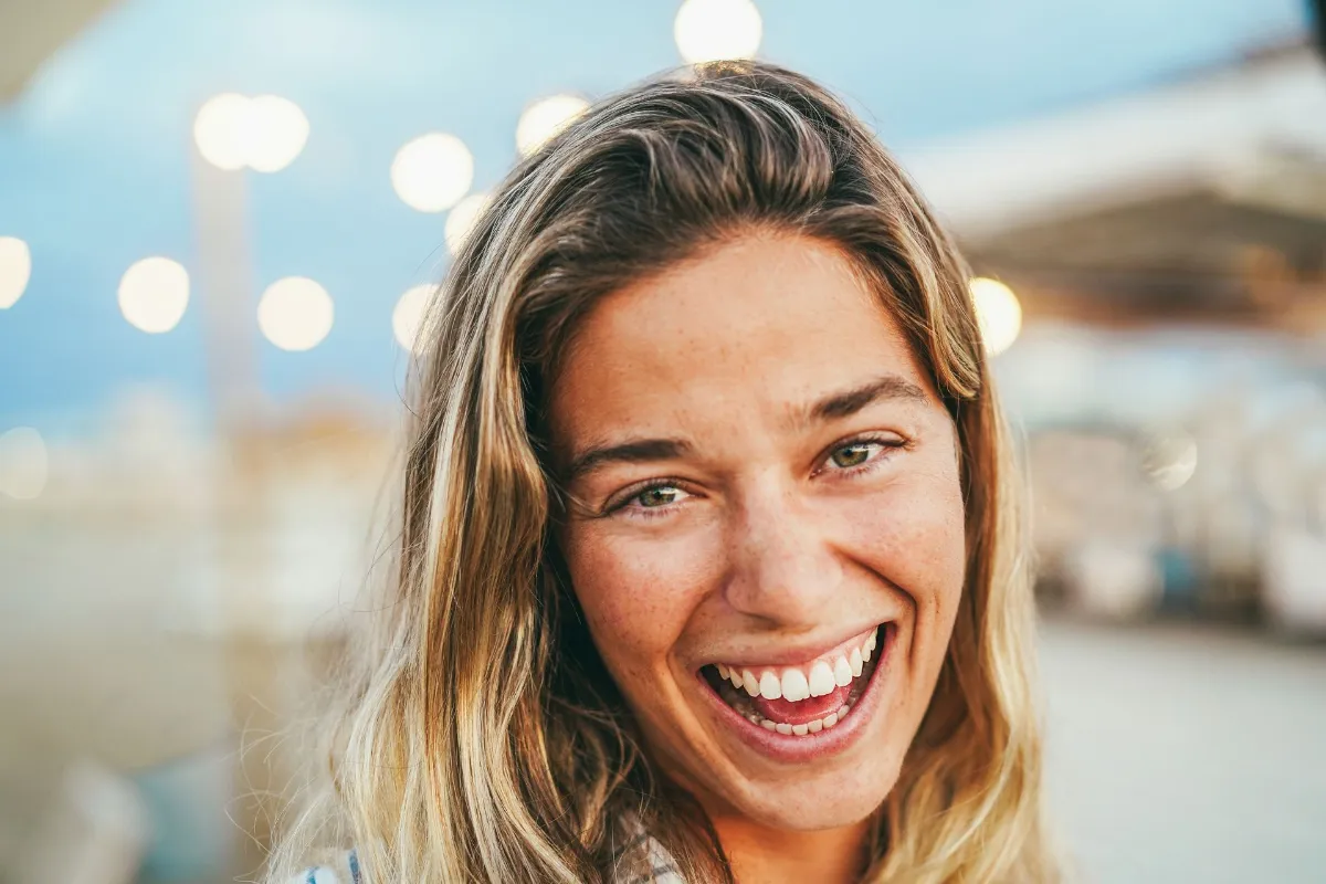 Young blond caucasian girl smiling on camera during beach party - Summer lifestyle