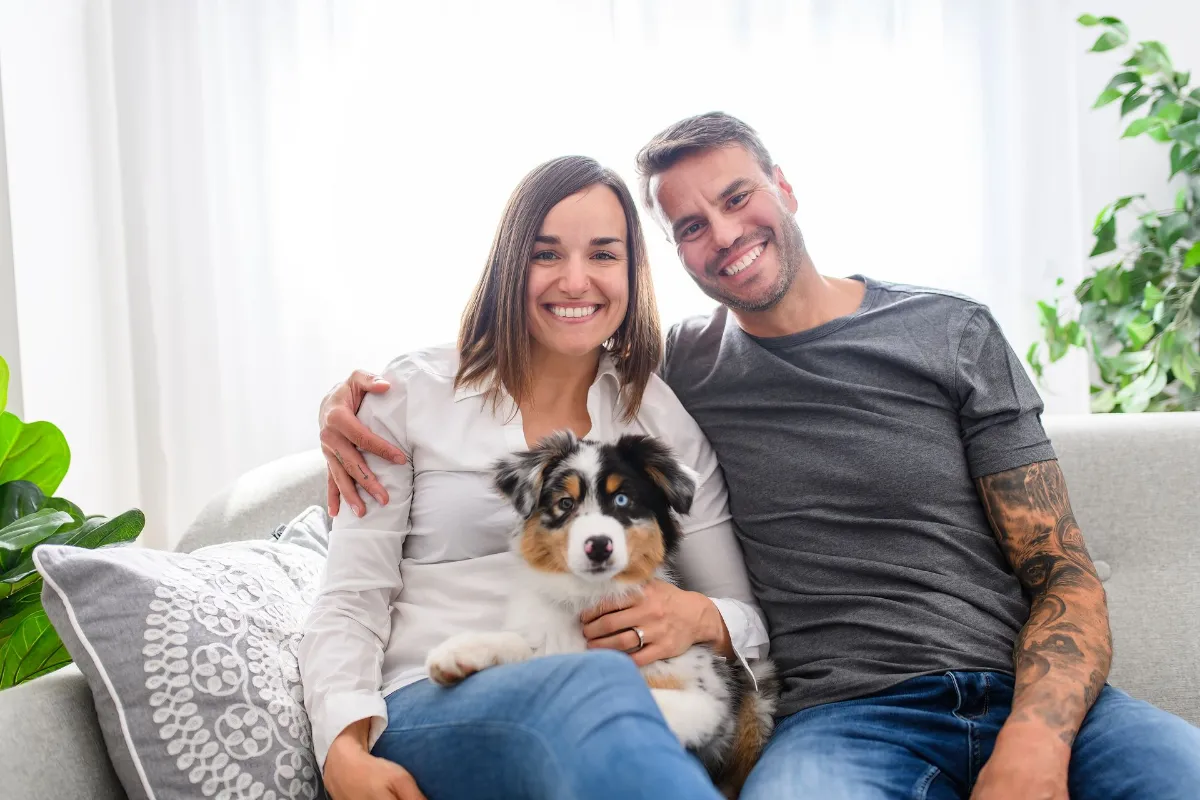 A Handsome couple with her Australian Berger puppy on sofa